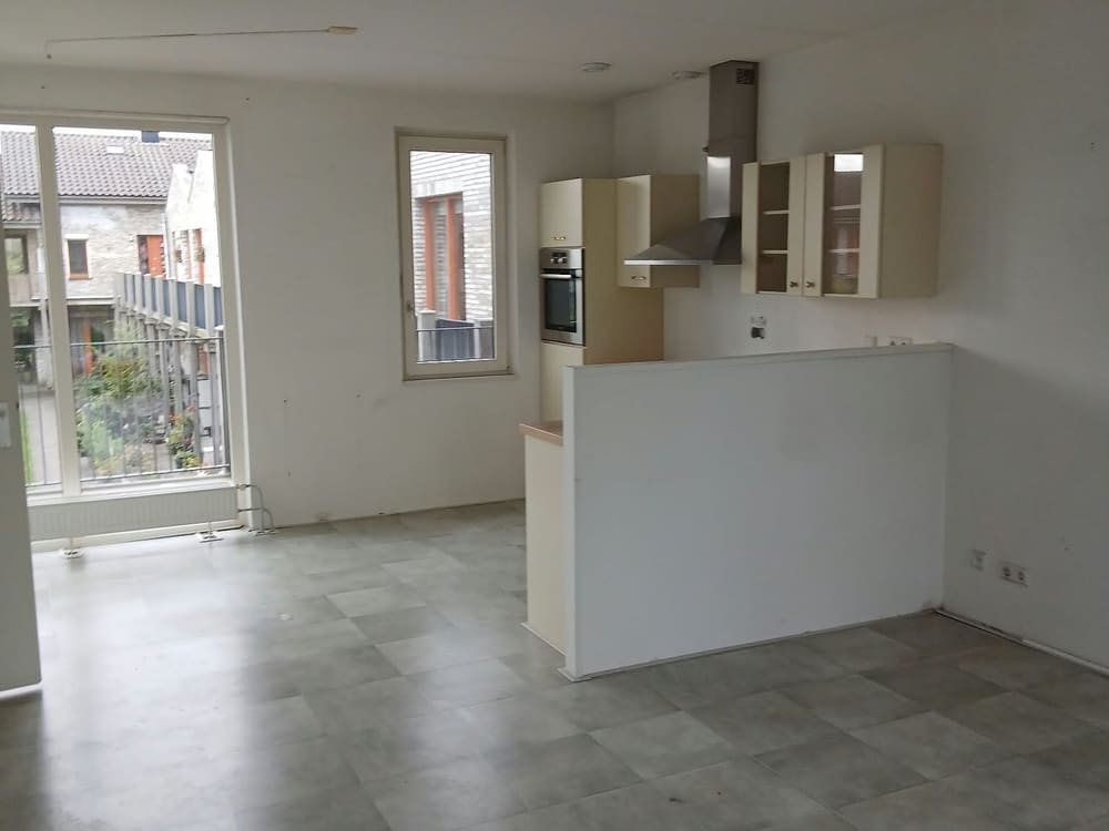 Leeggehaalde woonkamer met open keuken, bezemschoon opgeleverd